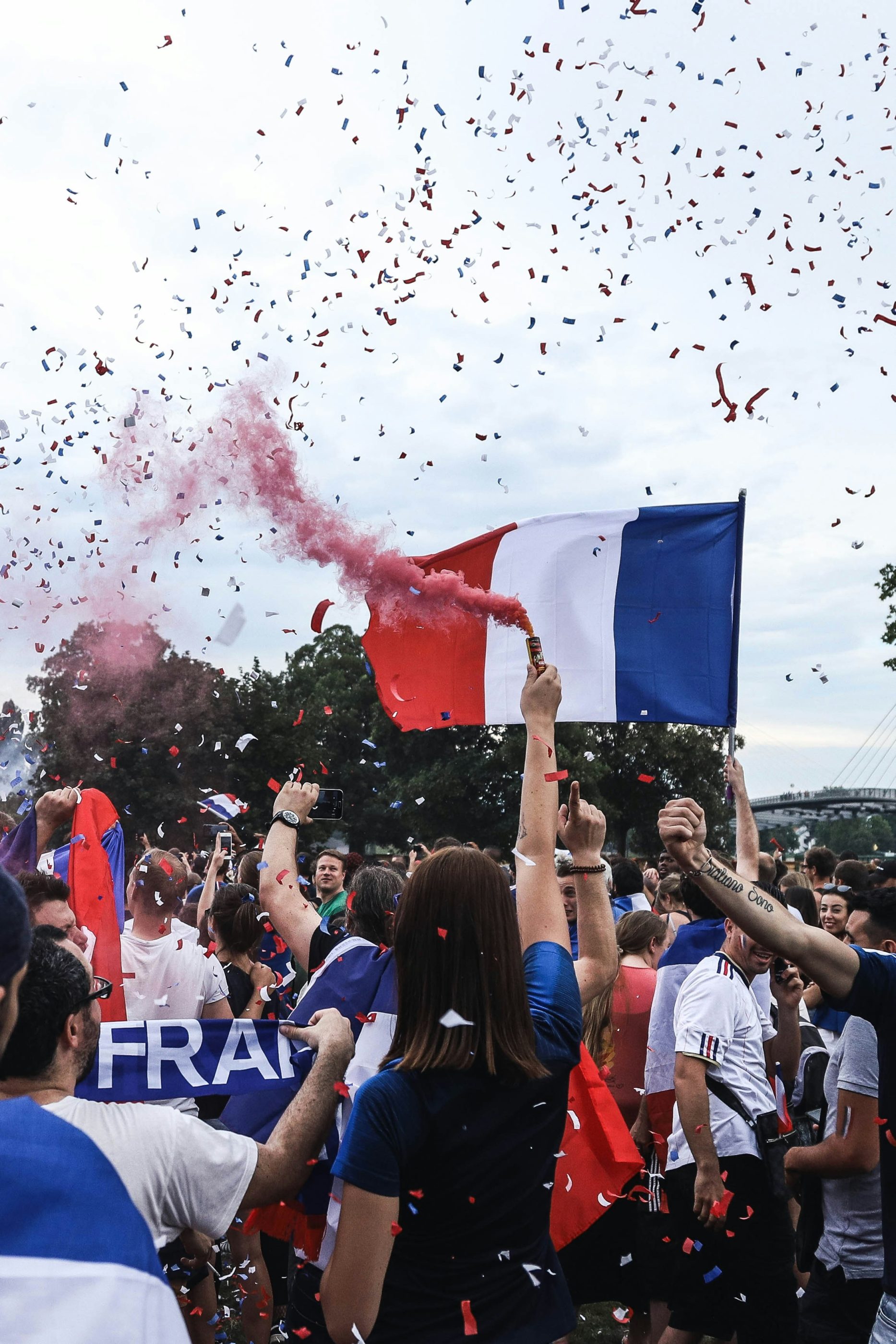Jour de match : des supporters sont présents de dos avec des drapeaux français, des confettis et des écharpes aux couleurs bleau-blanc-rouge